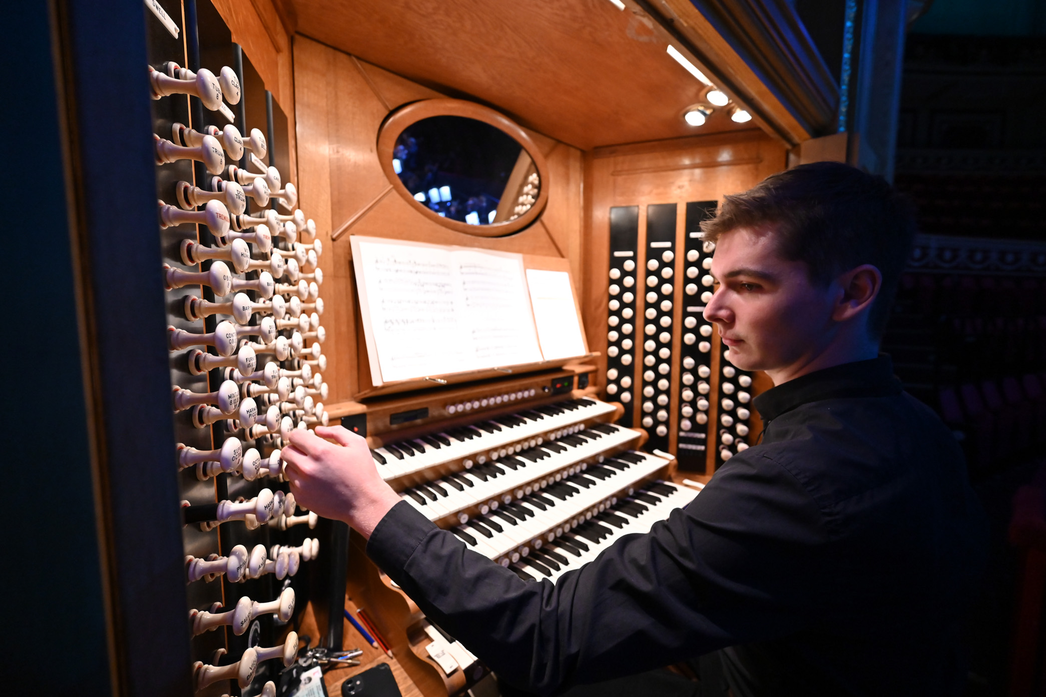 A male student in a black shirt, playing on the Royal Albert Hall organ during a performance at the BBC Proms.